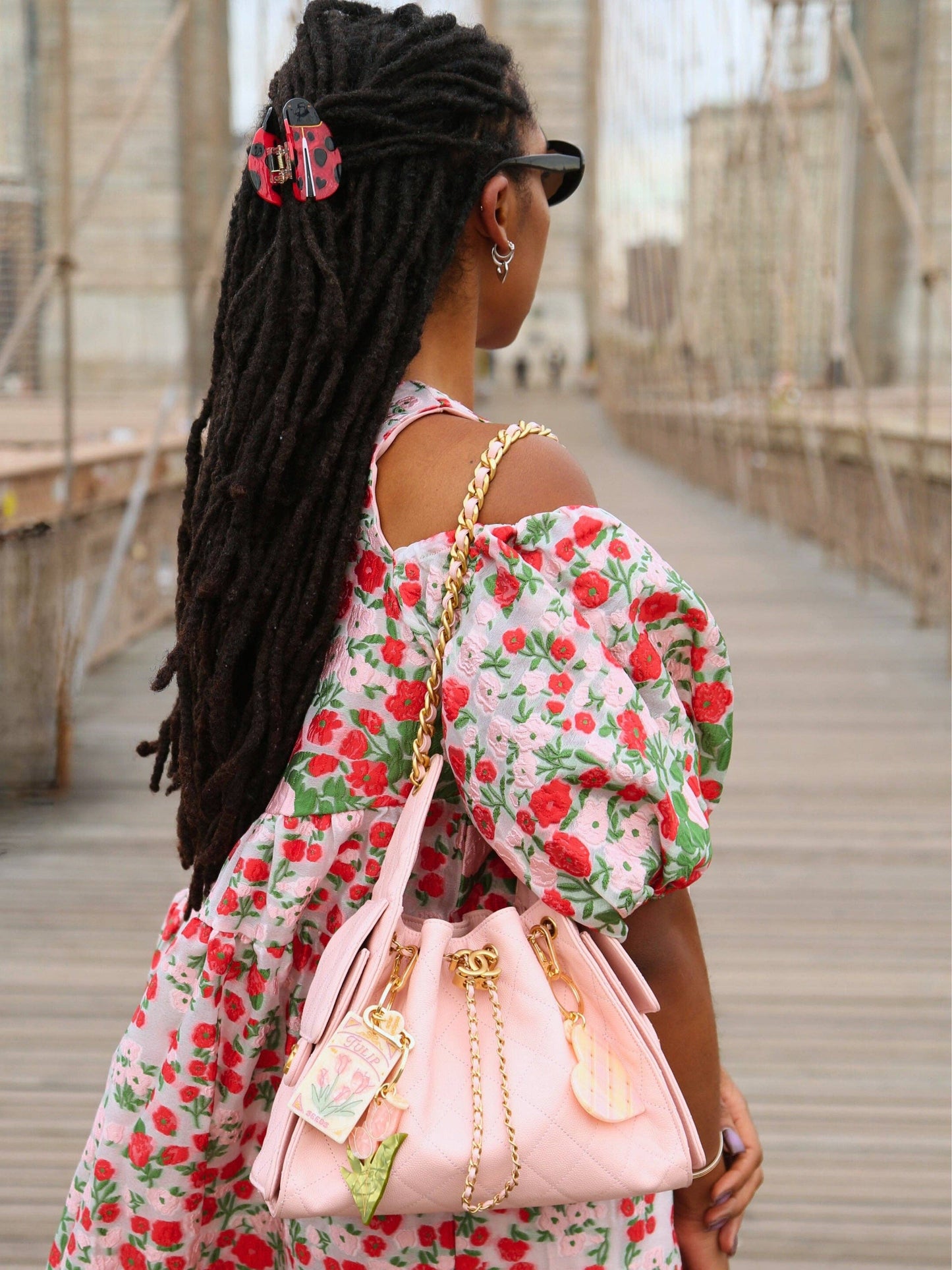 Woman in a floral dress with a pink handbag on a bridge