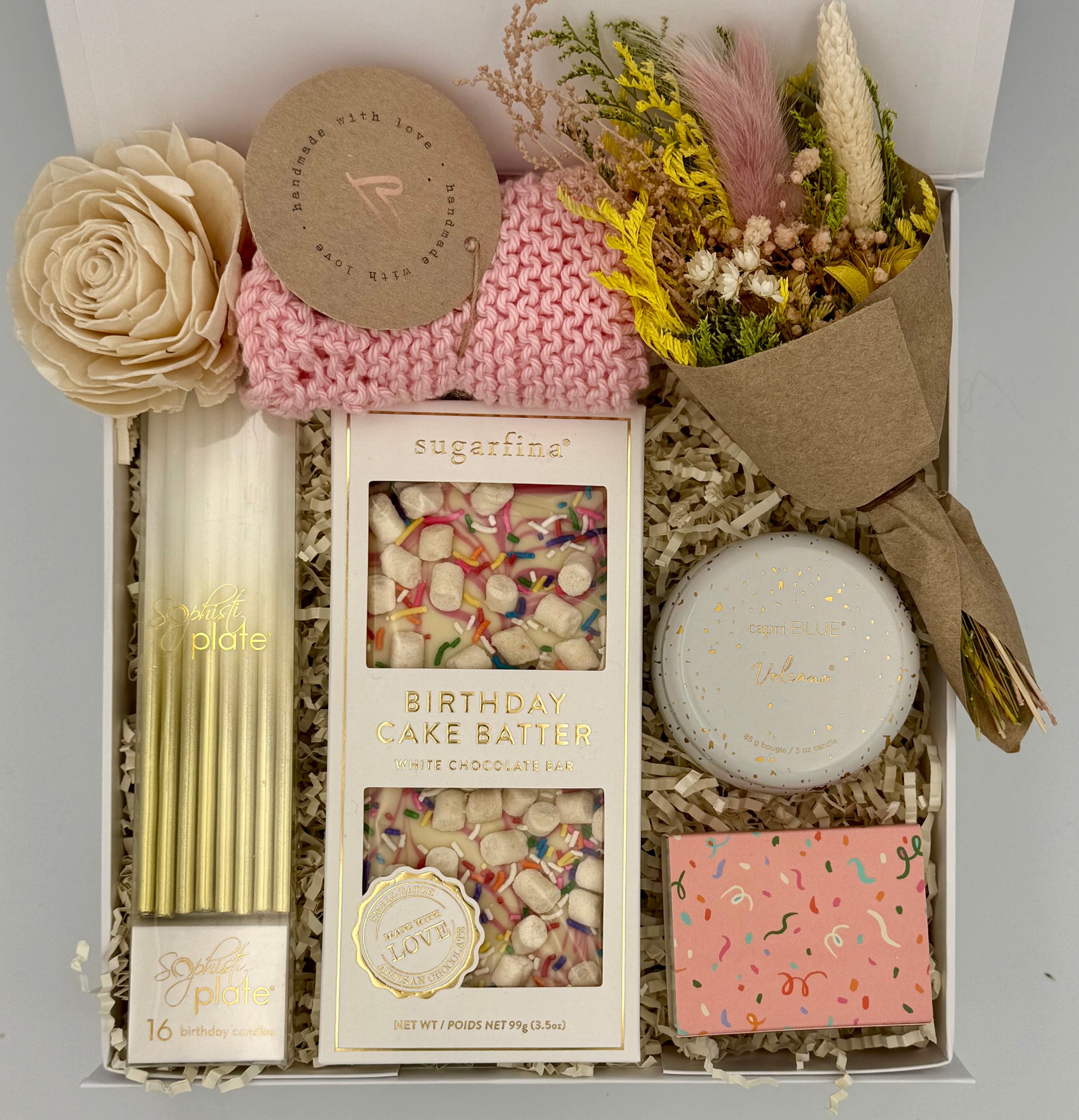 Gift box with birthday cake batter, candles, and decorative items on a gray background