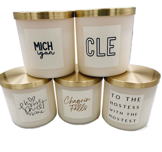 Five candles with gold lids and various text labels on a white background