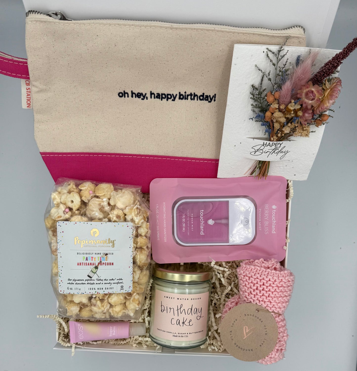 Gift set with a pouch, popcorn, candle, and other items on a gray background
