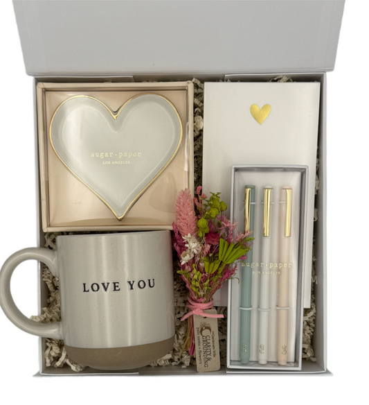 Gift set with mug, heart-shaped item, flowers, and stationery in a box