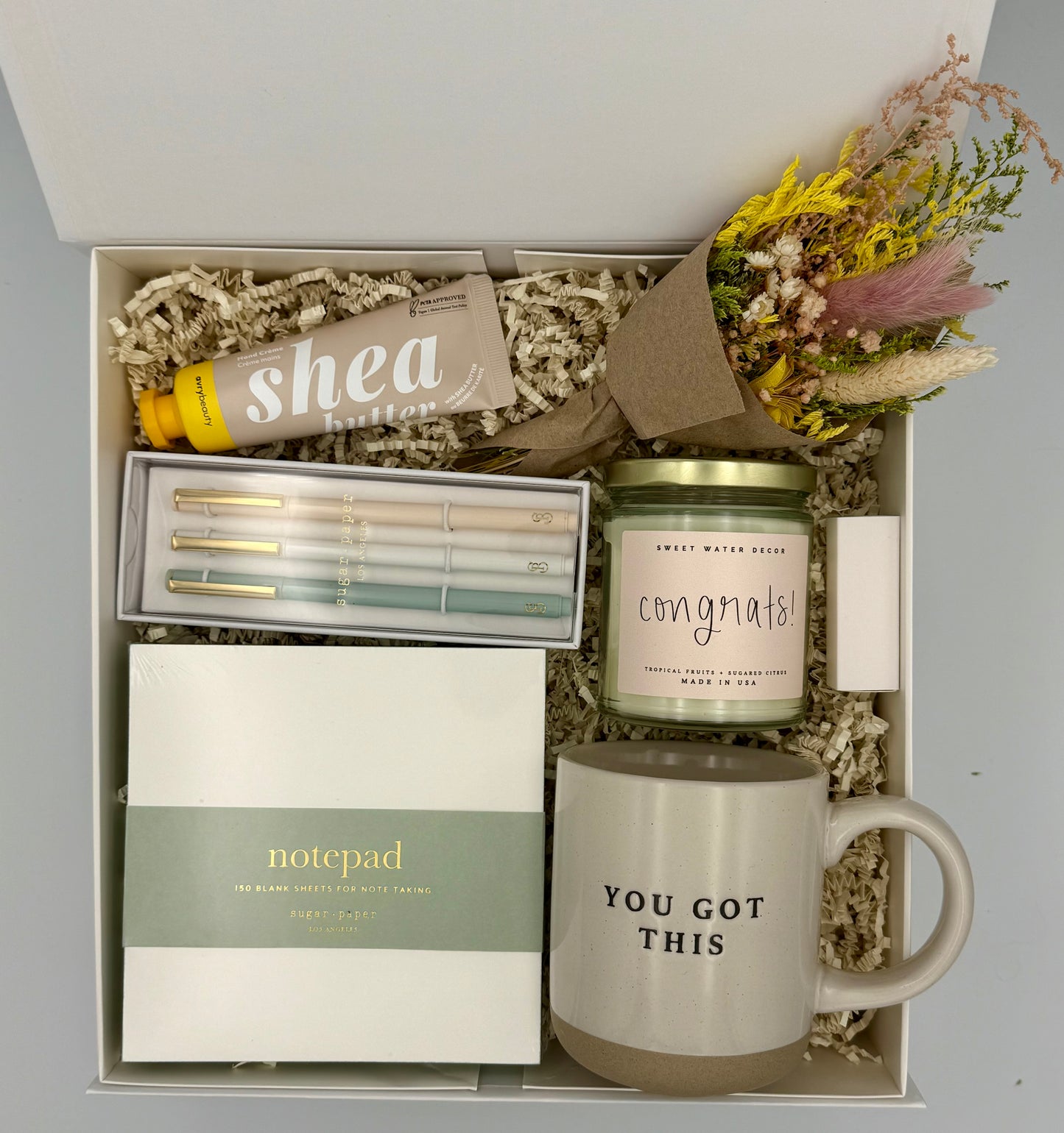 Gift set with mug, candle, notepad, and shea butter bar in a box.