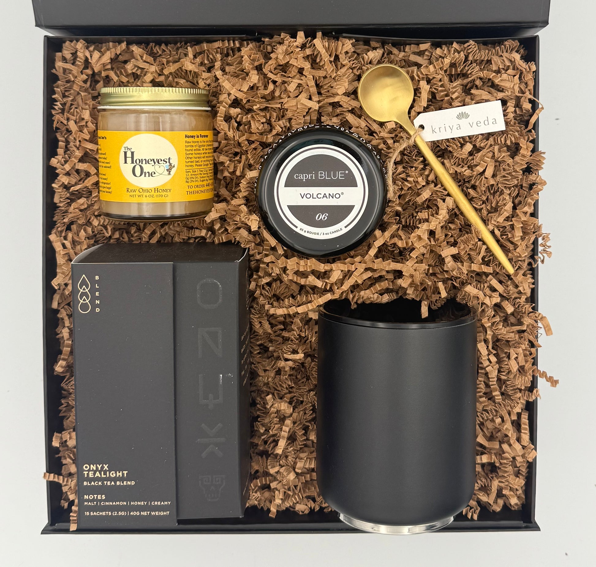 Gift set with a candle, tea light, and other items in a box with brown filler
