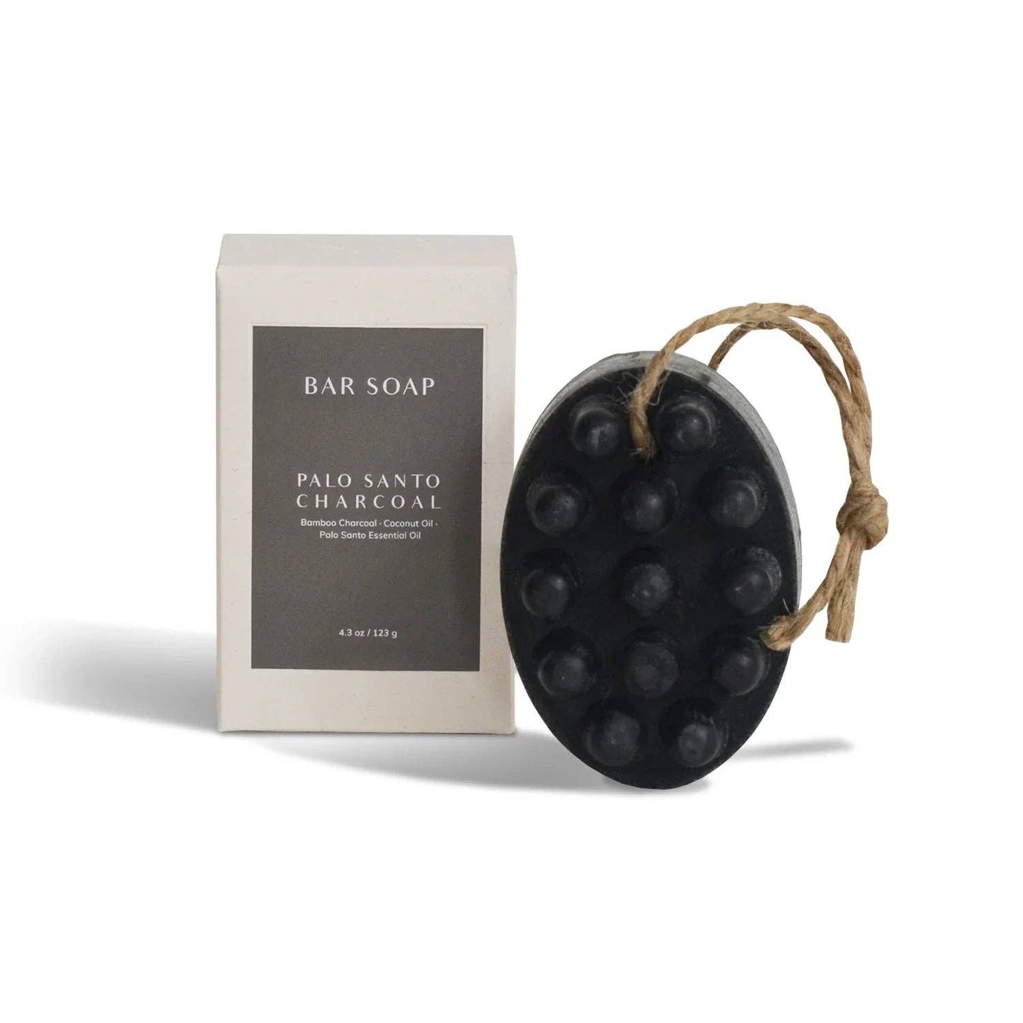 Black bar of soap on a rope with packaging labeled 'Palo Santo Charcoal' on a white background