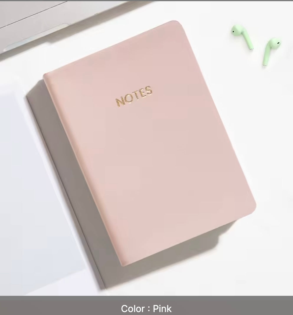 Pink notebook with 'NOTES' on a white surface
