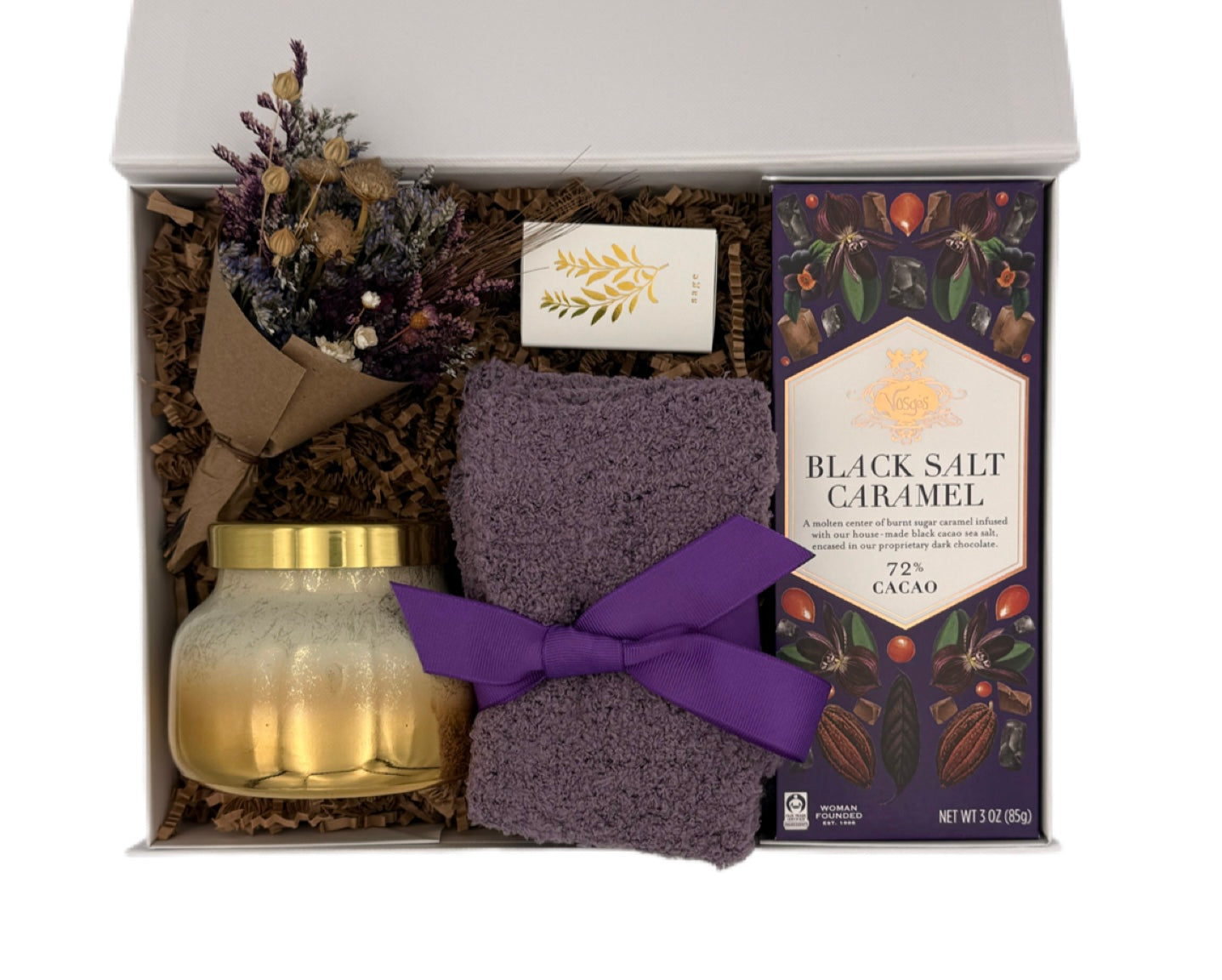 Gift set with a candle, soap, and chocolate bar in a decorative box.
