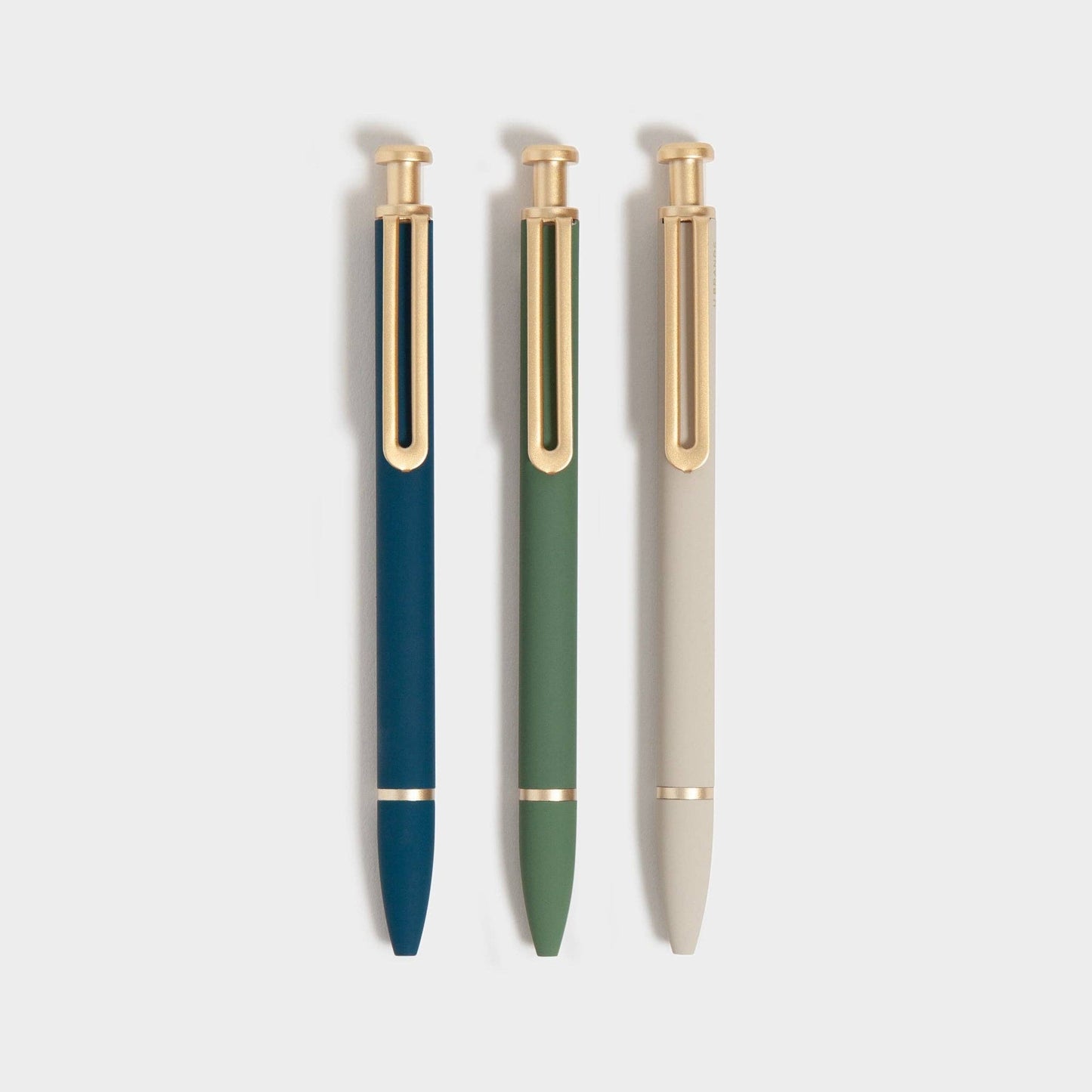 Three pens with gold accents on a light gray background