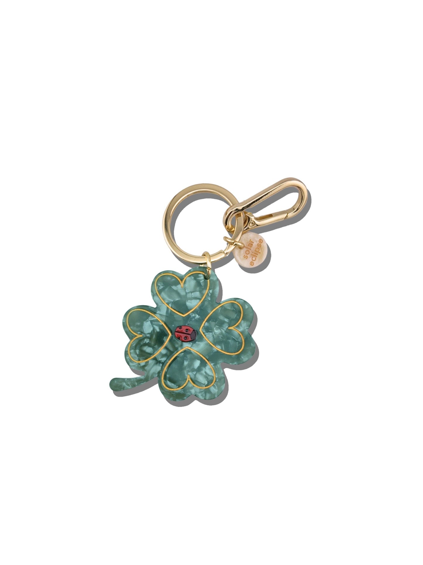 Gold keychain with a green clover-shaped charm on a white background