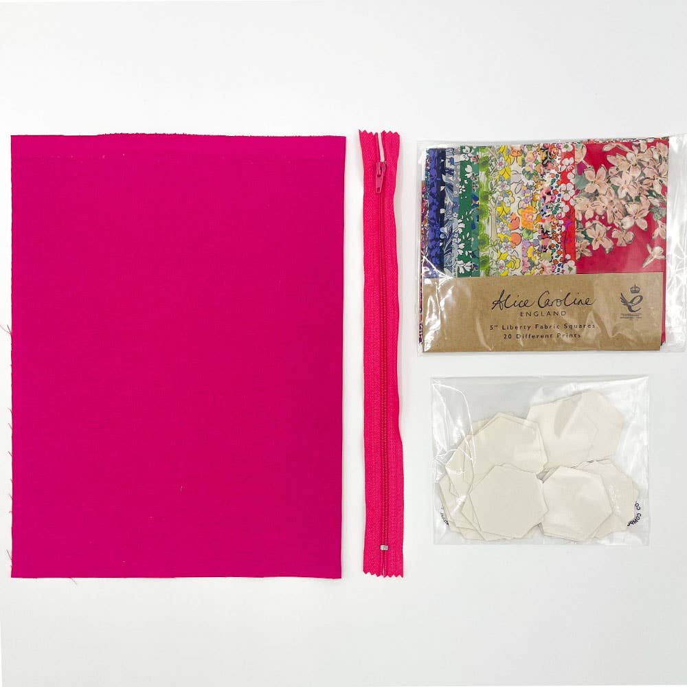 Pink fabric, zipper, and floral patterned paper on a white background