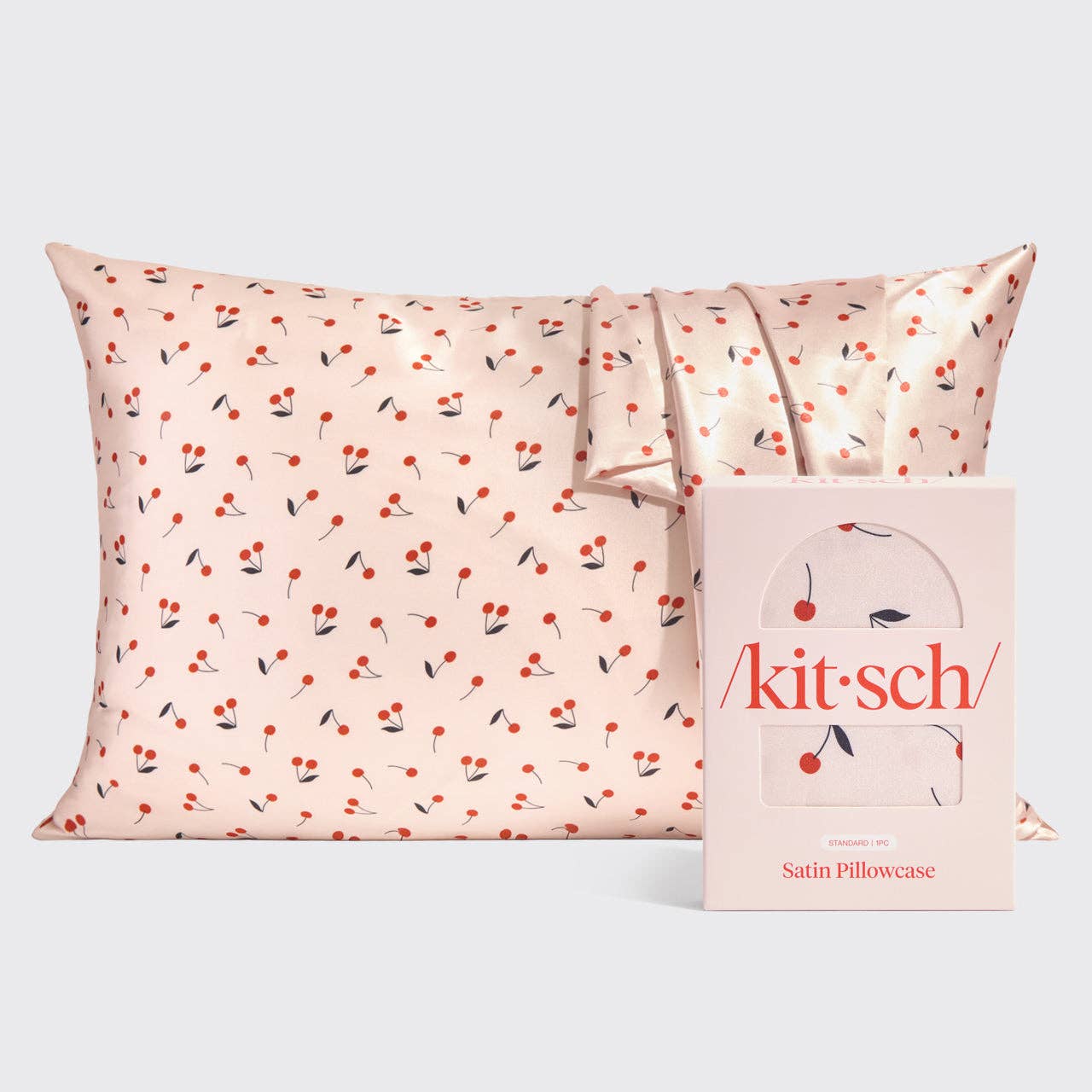 Satin pillowcase with cherry pattern and 'kitsch' packaging on a white background