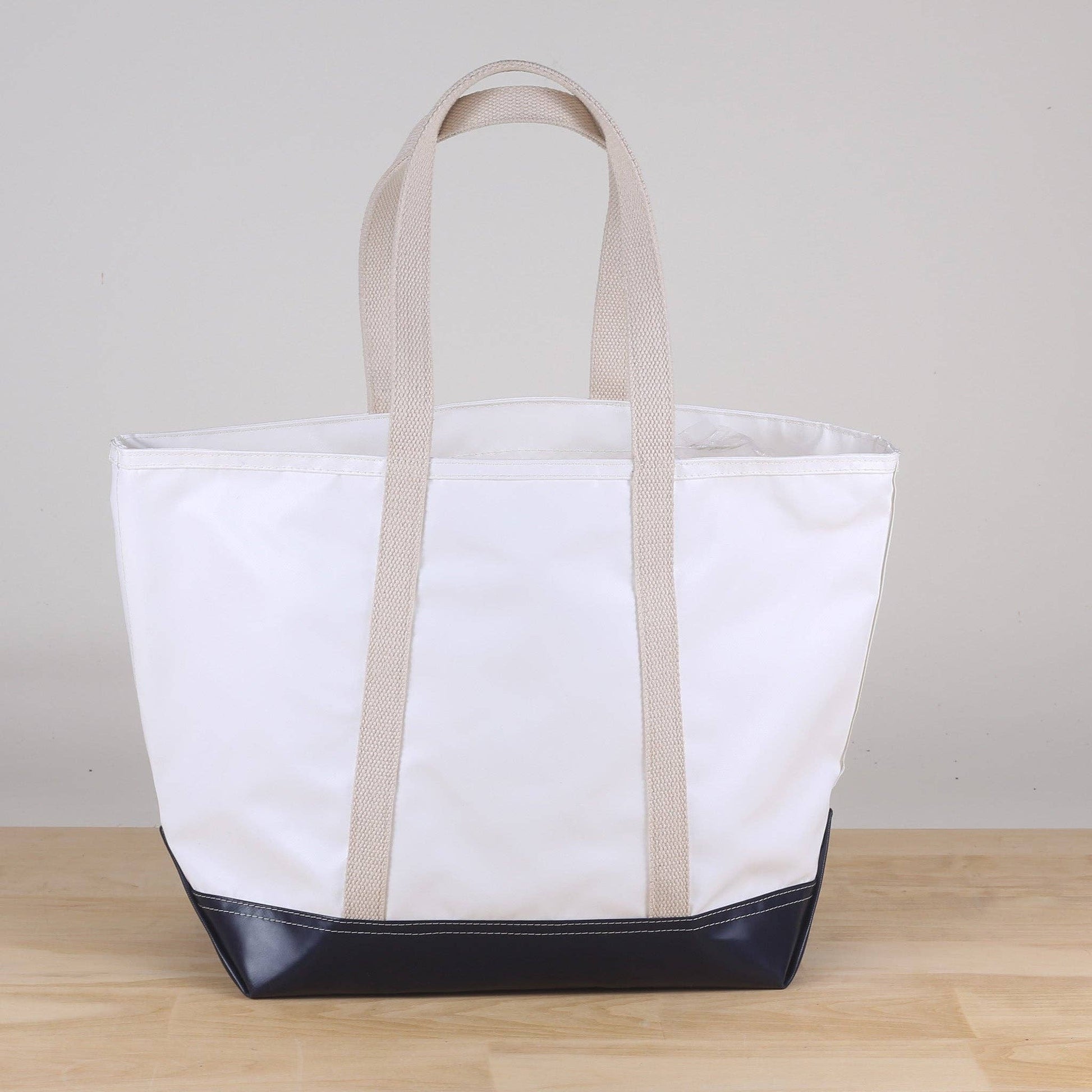 White tote bag with black bottom section on a wooden surface and light gray background