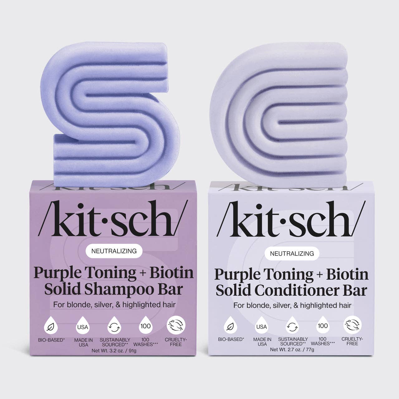 Two purple shampoo and conditioner bars with their packaging on a light gray background