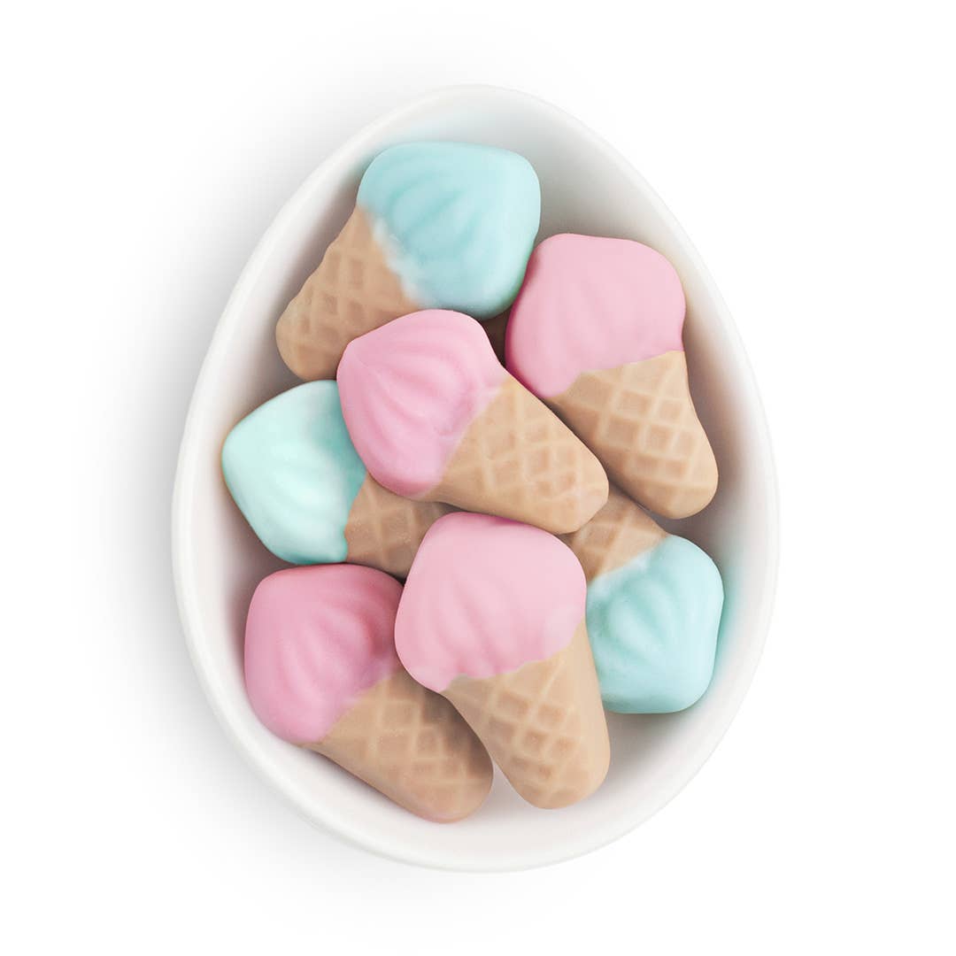 Pastel-colored ice cream cone-shaped candies in a white bowl on a white background