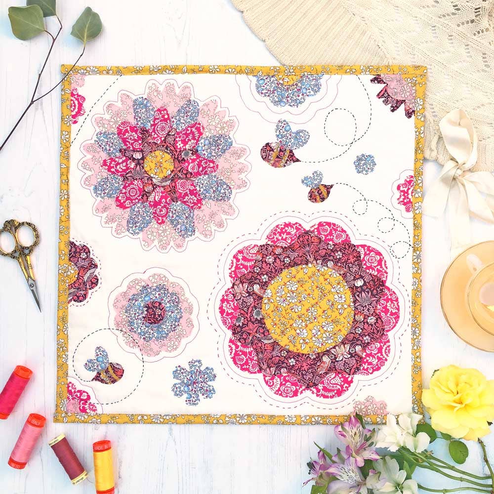 Floral patchwork design on a white background with sewing tools and flowers.