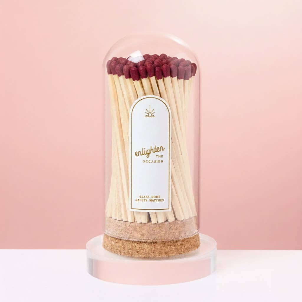 Matches in a glass dome with cork base on a pink background
