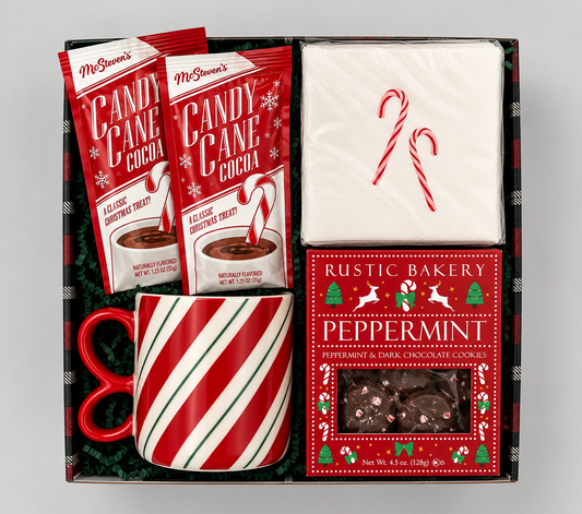 A holiday gift basket set in a black box with red and white striped candy cane motifs. The set includes two bags of McChicken's Candy Cane Cocoa, a white napkin with red candy cane drawings, a red and white striped mug, and a box of Rustic Bakery Peppermint chocolate cookies.