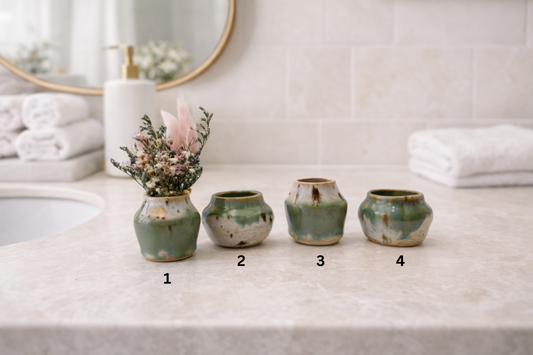 Four ceramic vases on a bathroom counter with numbers for reference