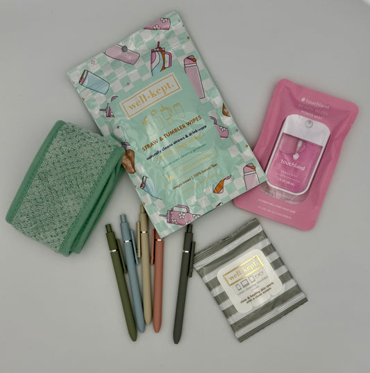 Collection of stationery items including pens, a notebook, and wipes on a light gray background