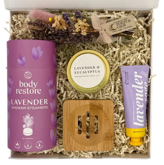 Gifting set with lavender-themed products including shower steamers, candle, and tube in a box.