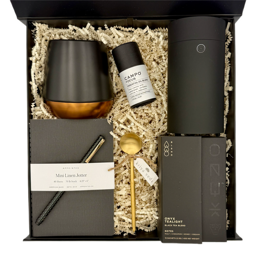 Gift set with black mug, bottle, and other items on a white background