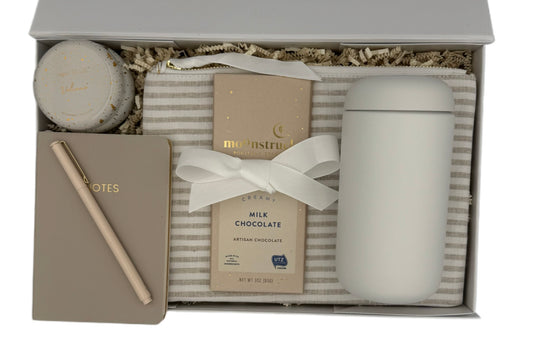 Gift set with a notebook, chocolate bar, and candle in a decorative box.