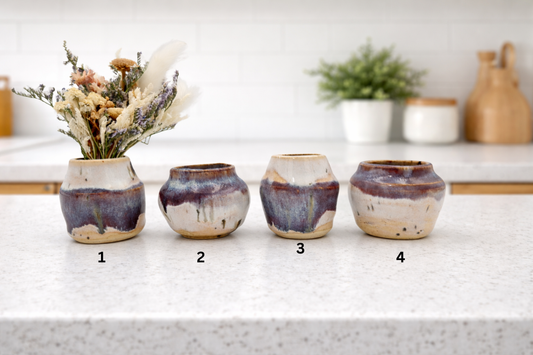 Four ceramic vases on a white surface with a blurred background