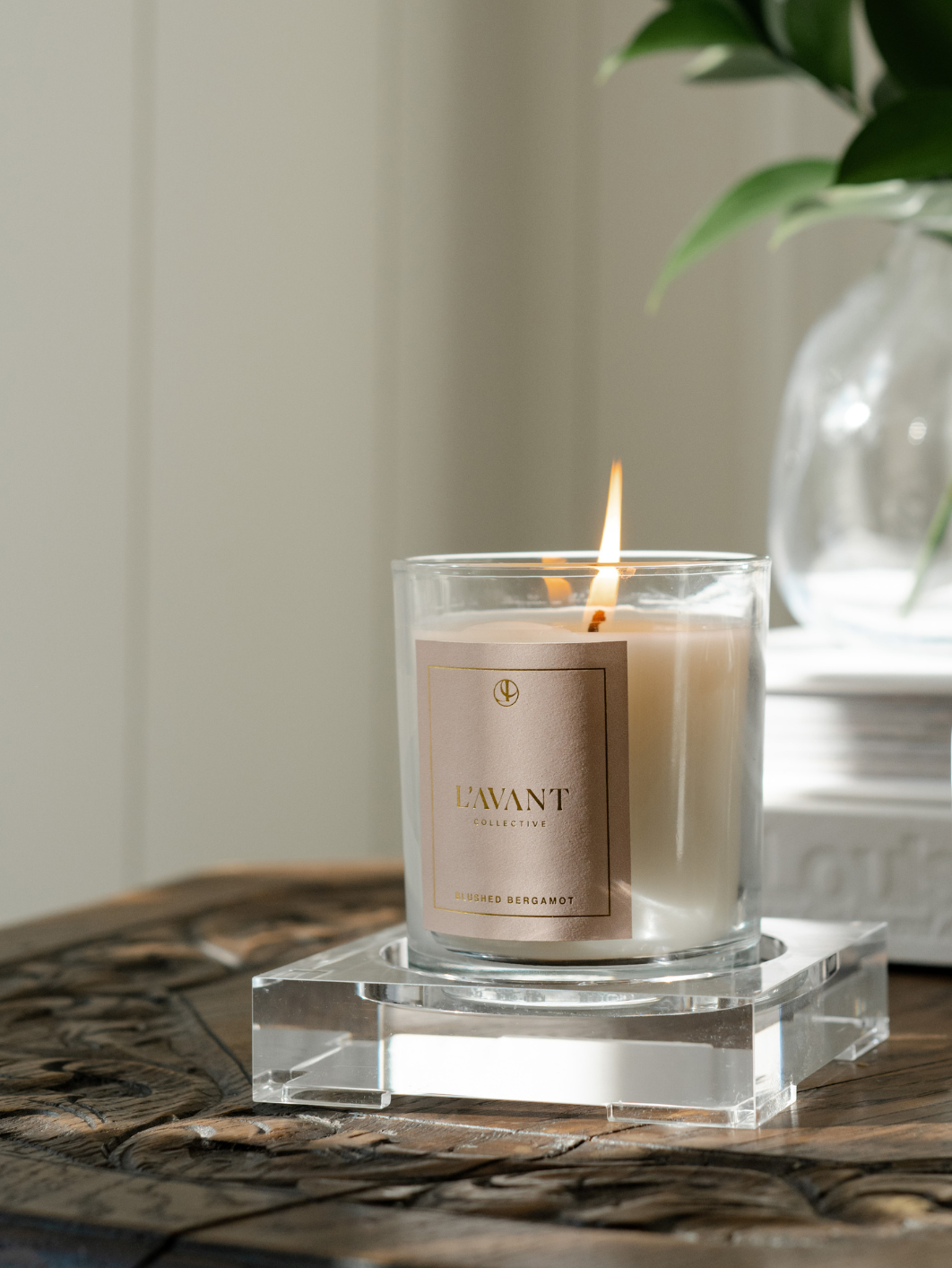 Candle with a visible brand label on a clear glass stand, with a blurred background