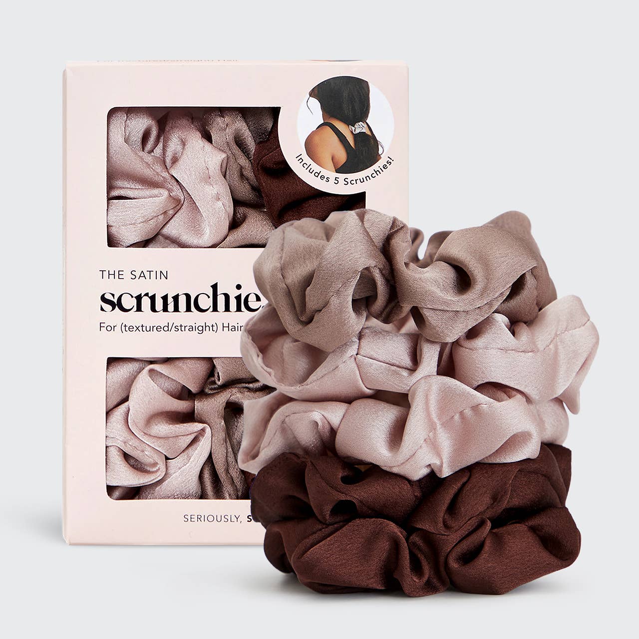Set of satin scrunchies in pink, brown, and beige with packaging on a light gray background