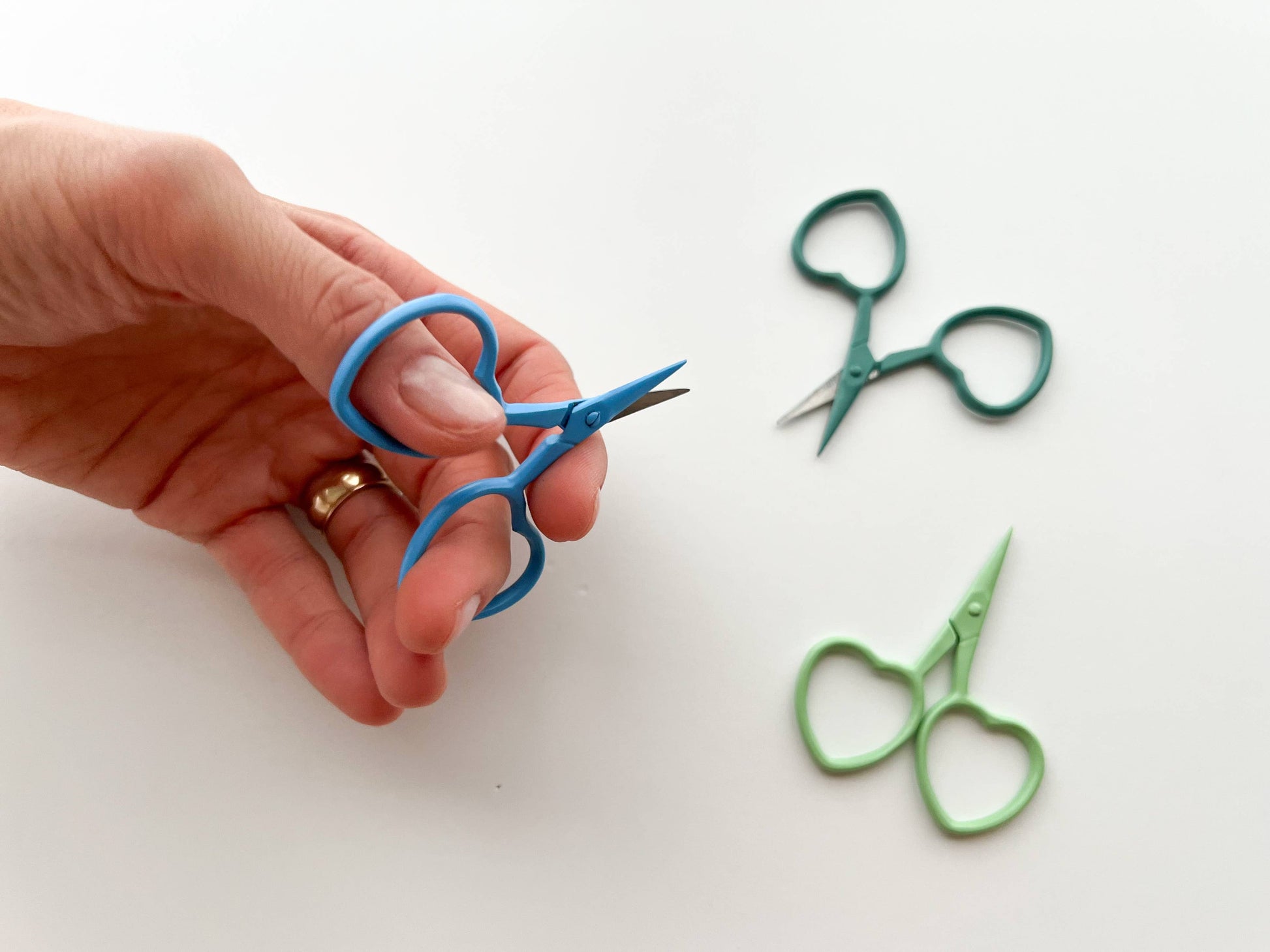 Hand holding blue scissors with blue scissors on a white background
