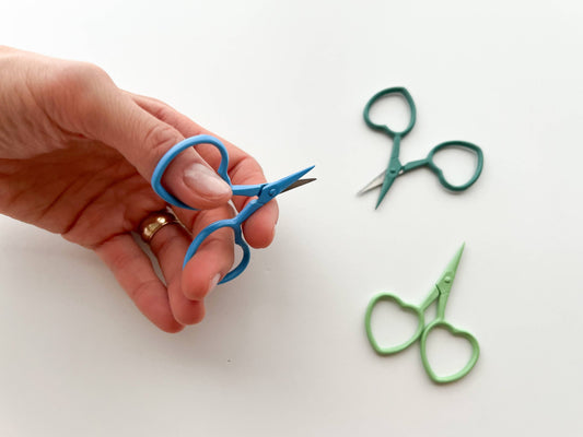 Hand holding blue scissors with blue scissors on a white background