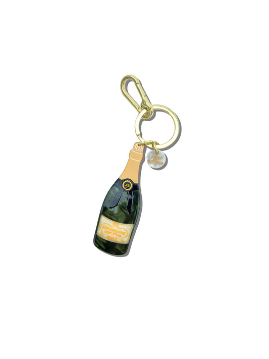Champagne bottle keychain with gold clip on a white background