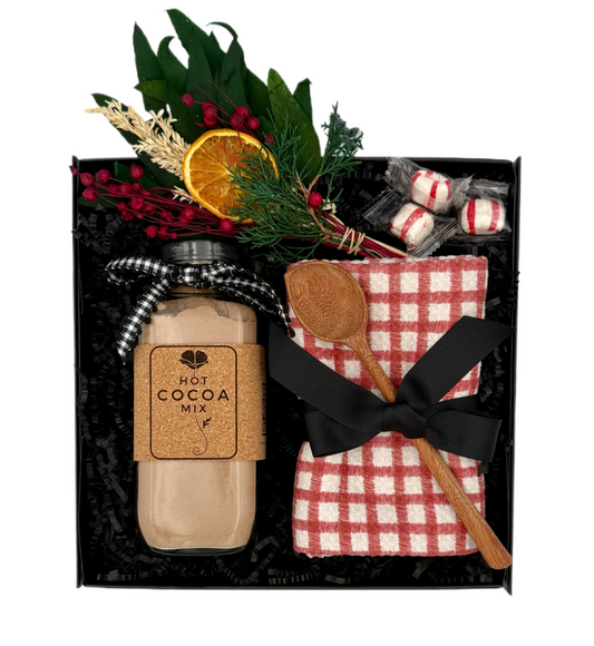 Hot cocoa mix gift set with a jar, spoon, and decorative elements in a black box.
