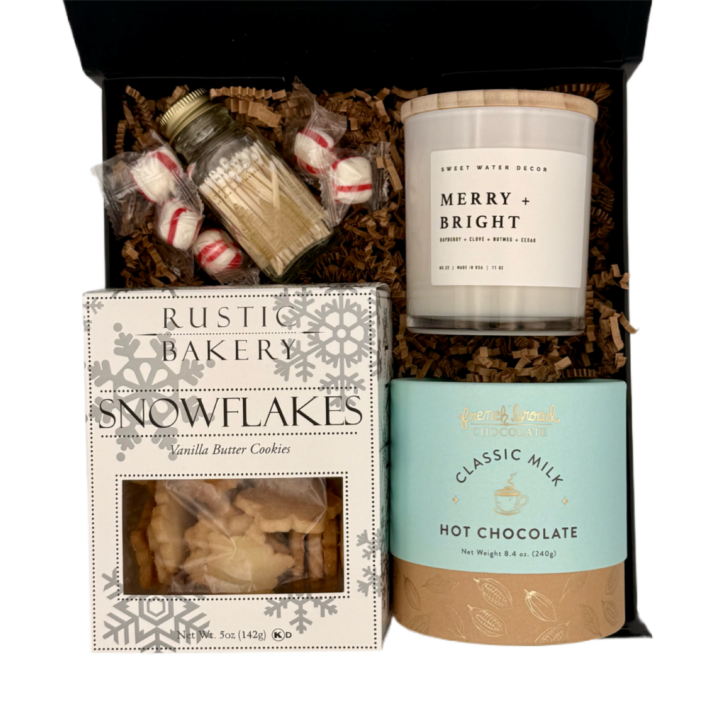 Gift set with a candle, hot chocolate mix, and cookies in a decorative box.