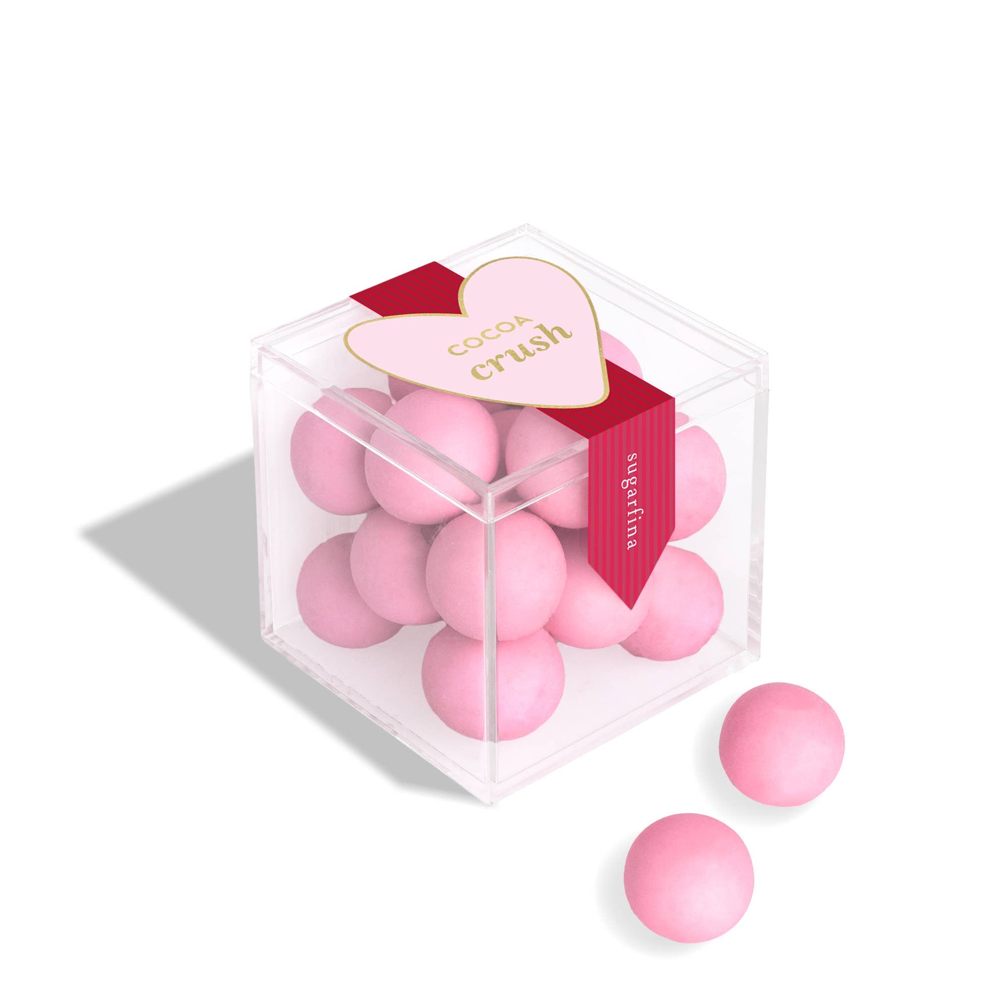 Pink candies in a transparent box with a heart-shaped label on a white background