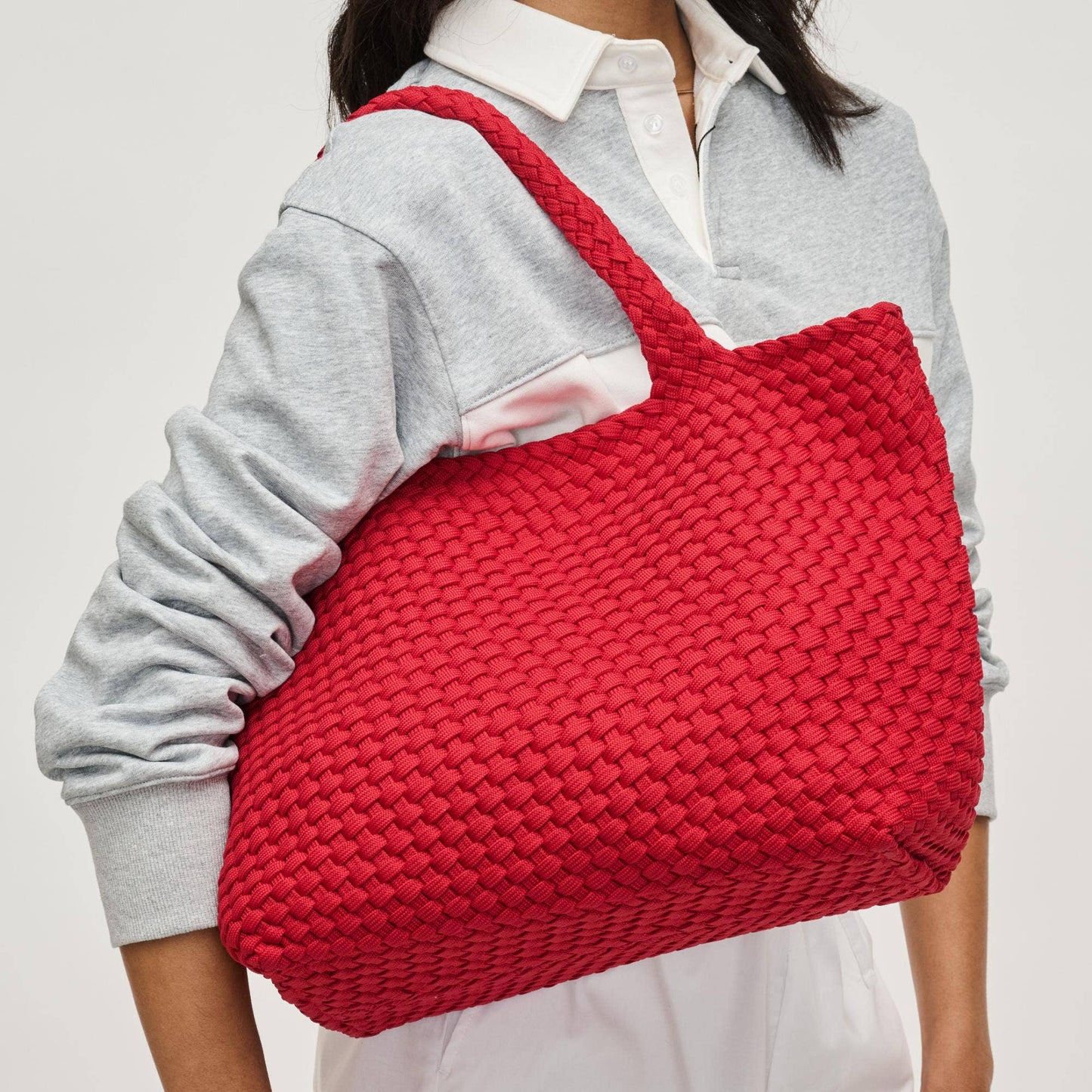 Person holding a red woven bag against a plain background