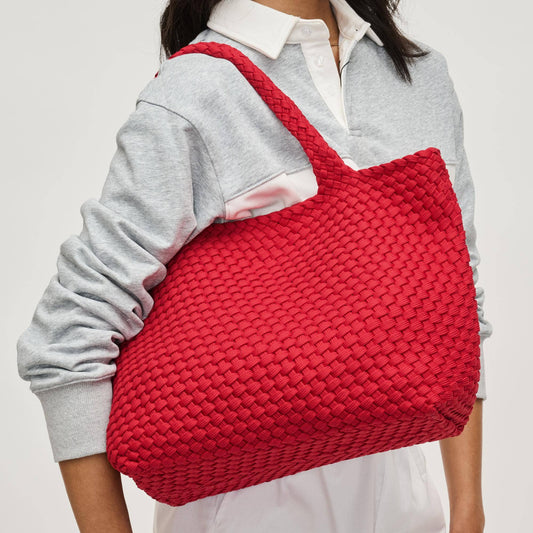 Person holding a red woven bag against a plain background