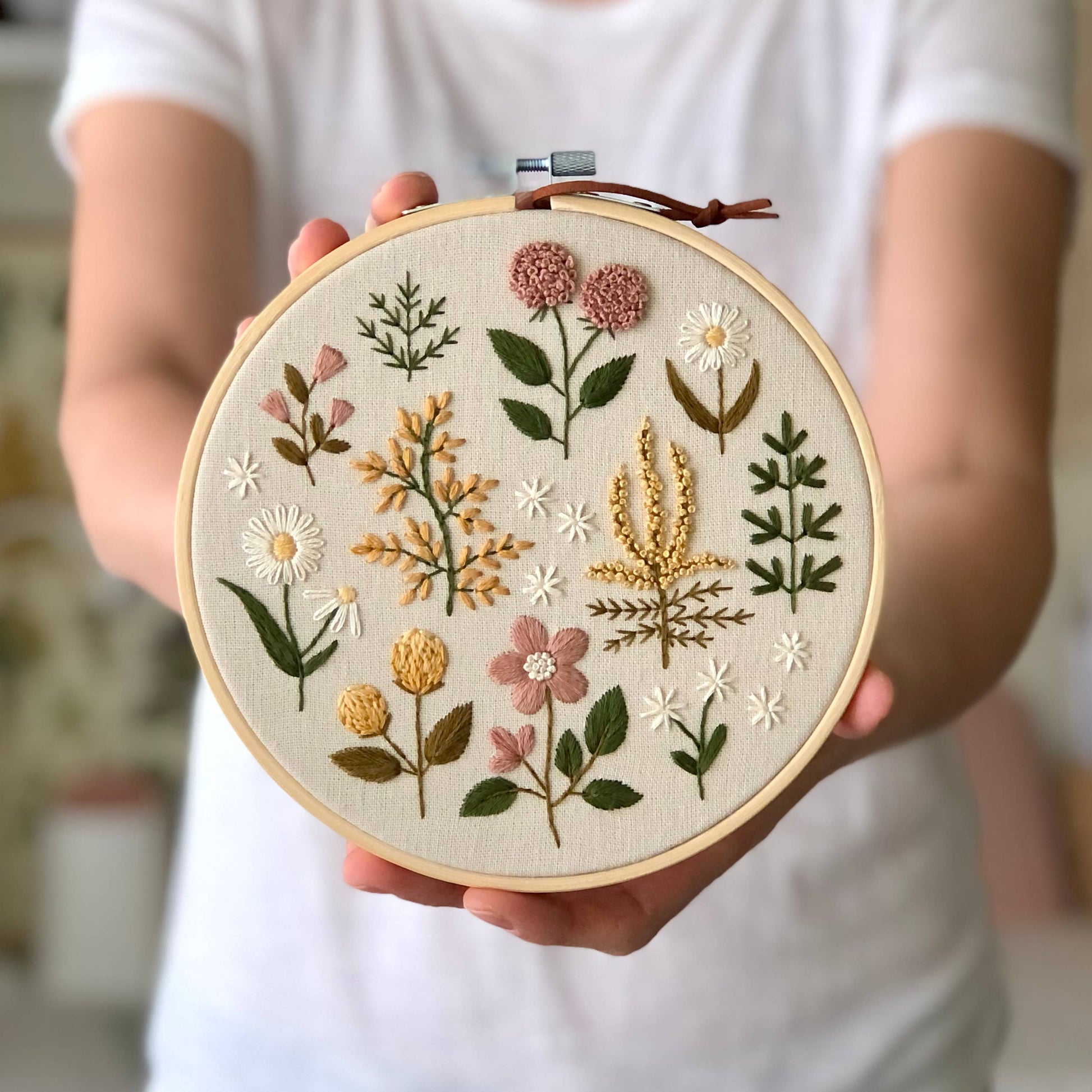 Embroidery hoop with floral patterns held by a person