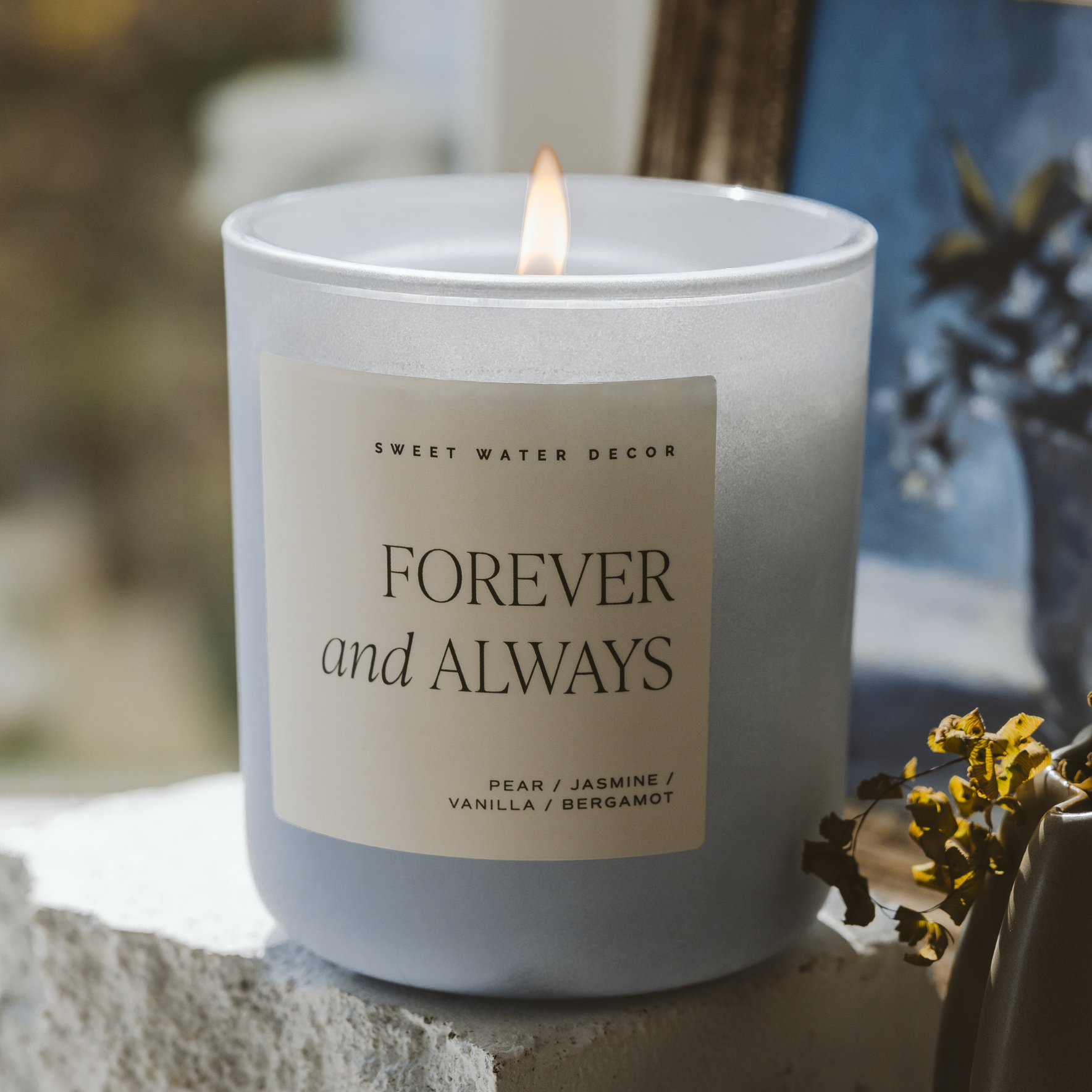 Candle with 'Forever and Always' label on a stone surface with blurred background