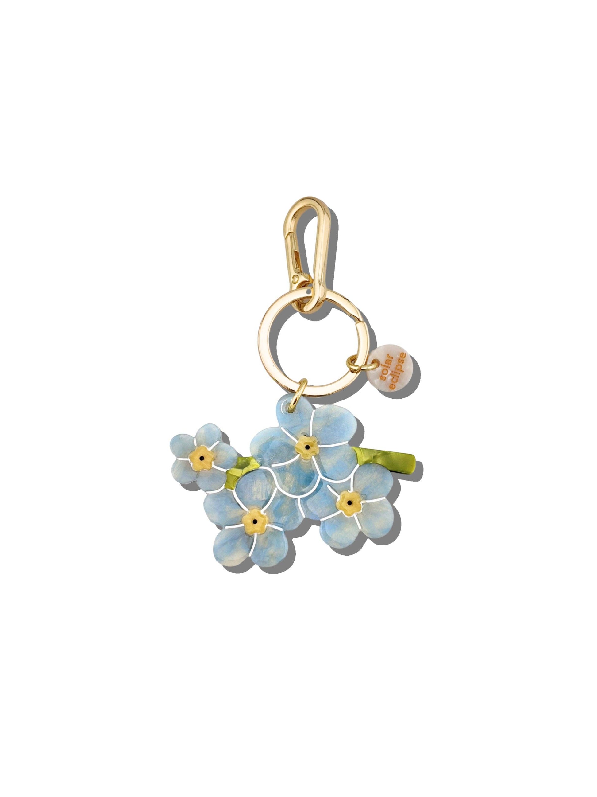 Gold charm with blue floral design on a white background