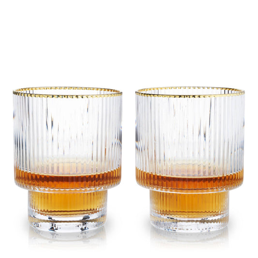 Two glasses with gold rims and orange liquid on a white background