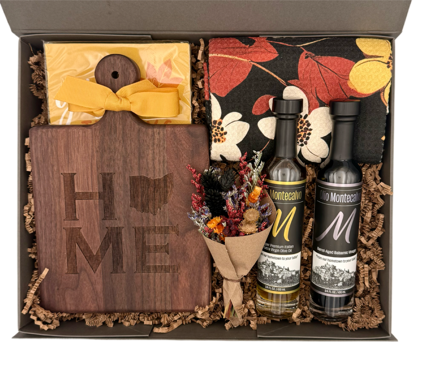 Gift box with wooden cutting board, Montecarlo wine bottles, and decorative items.