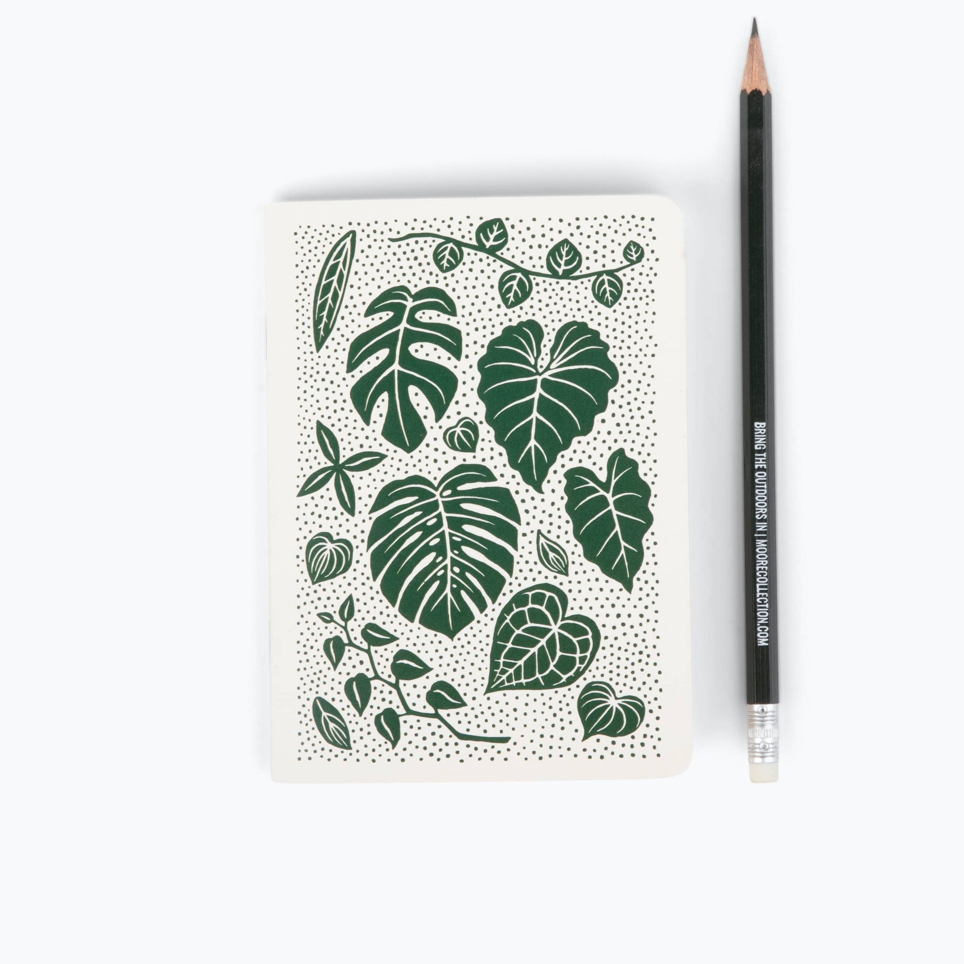 Notebook with green leaf pattern and a pencil on a white background