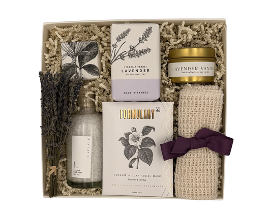 Gift set with lavender-themed products including soap, candle, and towel in a box.
