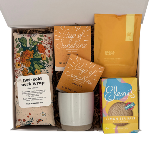 Gift box containing a neck wrap, tea packages, a mug, and cookies.