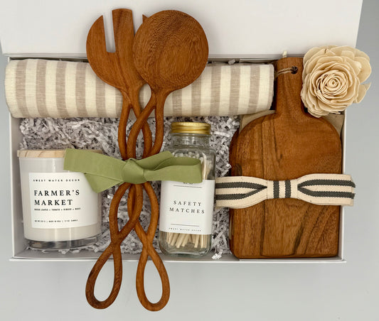 Gift set with wooden spoons, candle, matches, and cutting board in a box.
