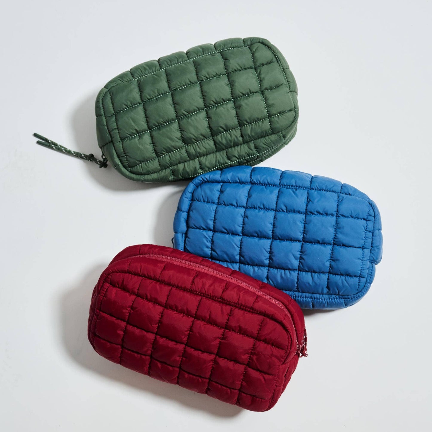 Three quilted pouches in green, blue, and red on a light gray background