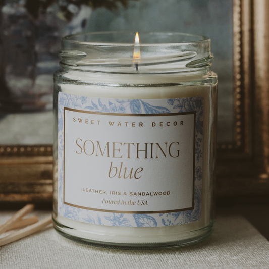 Candle in a glass jar with a decorative label on a textured surface