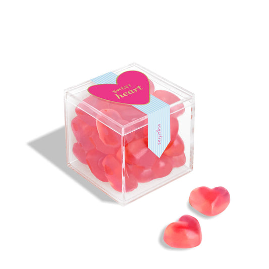 Clear cube container filled with heart-shaped red candies on a white background
