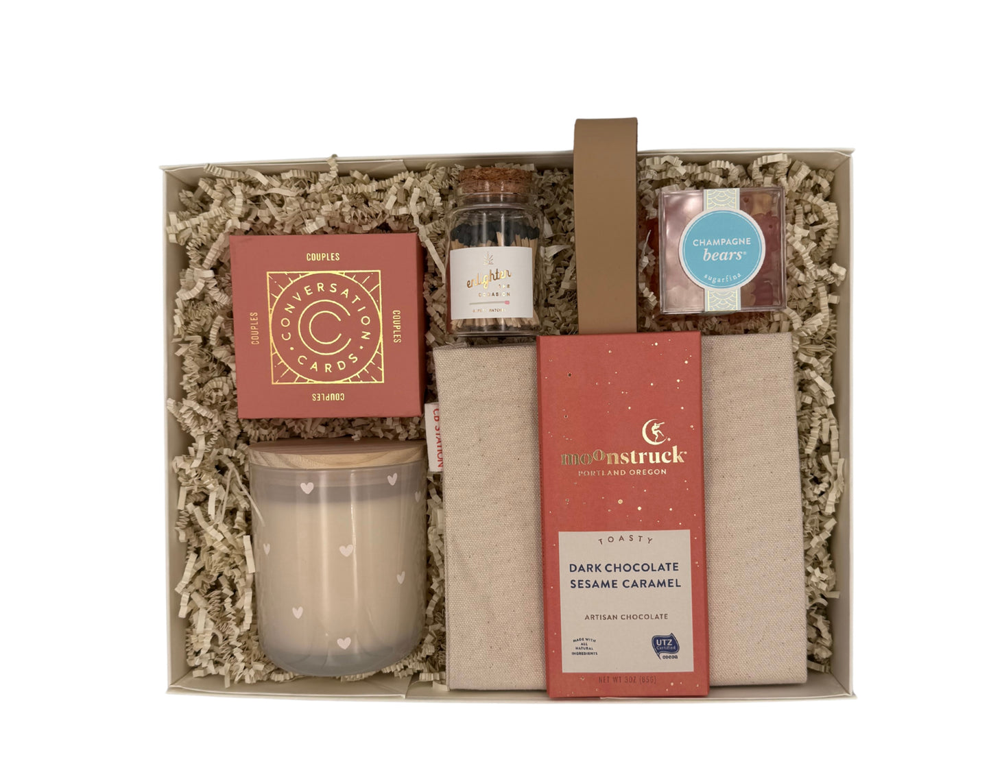 Gift set with a candle, chocolate bar, and cards in a decorative box.